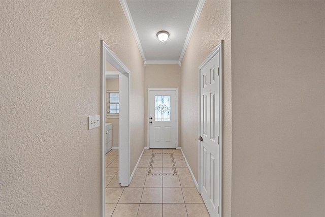entryway featuring baseboards, ornamental molding, a textured wall, and light tile patterned flooring