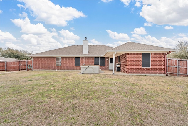back of house featuring a fenced backyard, roof with shingles, brick siding, and a patio area
