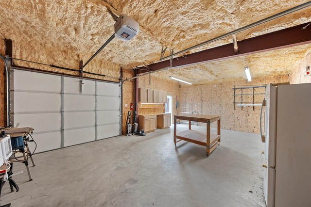 garage featuring freestanding refrigerator and a garage door opener