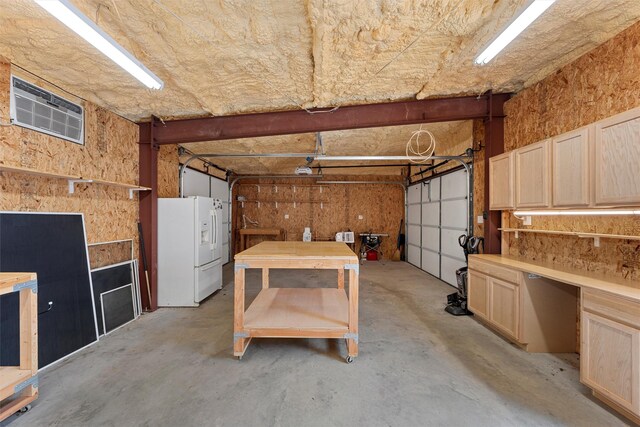 garage with white refrigerator with ice dispenser and a workshop area