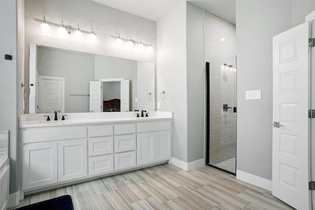 bathroom with a shower stall, connected bathroom, a sink, and double vanity
