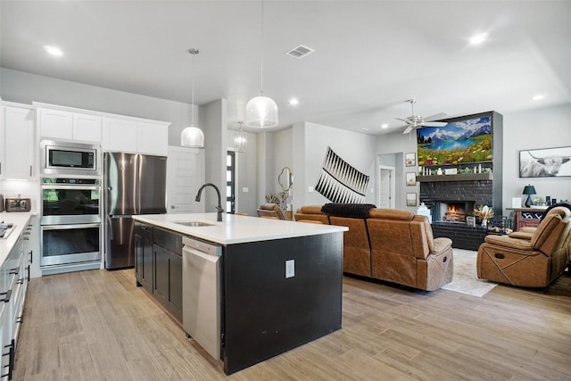 kitchen featuring light countertops, a sink, light wood-style flooring, appliances with stainless steel finishes, and white cabinetry