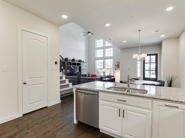 kitchen with dark wood finished floors, light stone counters, stainless steel dishwasher, a sink, and open floor plan
