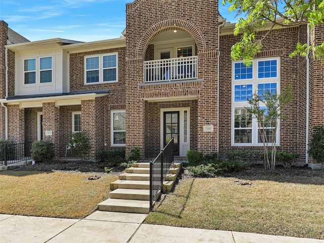 view of front of house with a front lawn, a balcony, and brick siding