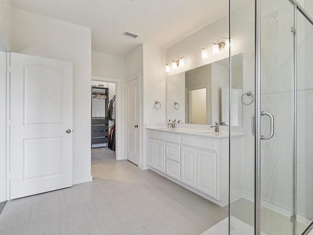 full bathroom featuring a shower stall, a walk in closet, a sink, and visible vents