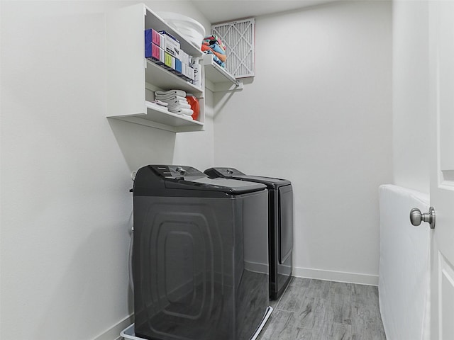 laundry room featuring light wood-style floors, baseboards, washer and dryer, and laundry area