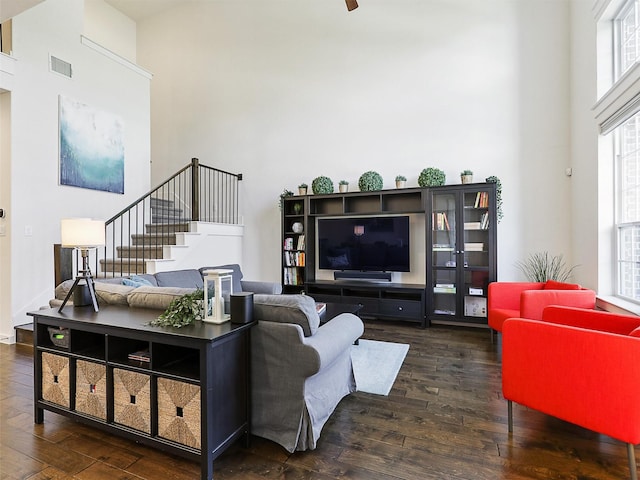 living room featuring wood finished floors, visible vents, a high ceiling, and stairs