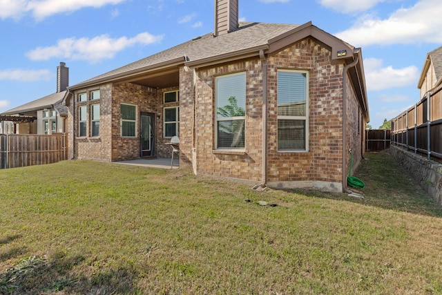 back of property featuring a fenced backyard, a chimney, and brick siding