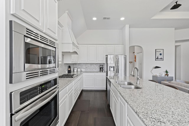 kitchen featuring a sink, appliances with stainless steel finishes, white cabinetry, light stone countertops, and visible vents