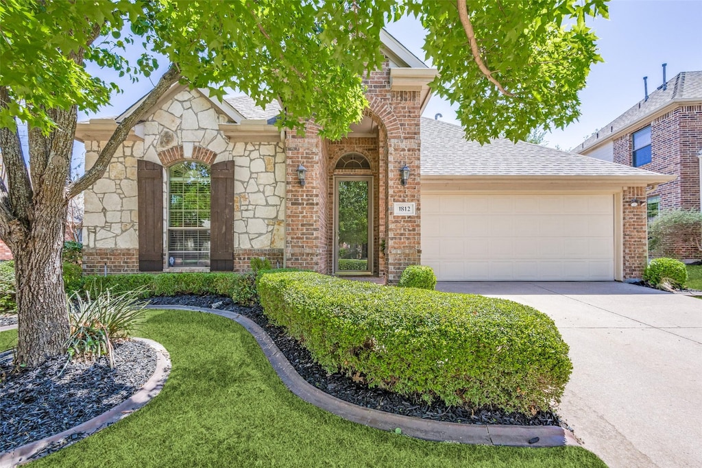 view of front of house featuring concrete driveway, brick siding, stone siding, roof with shingles, and a garage