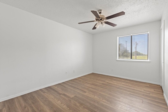 empty room with baseboards, a ceiling fan, wood finished floors, and a textured ceiling