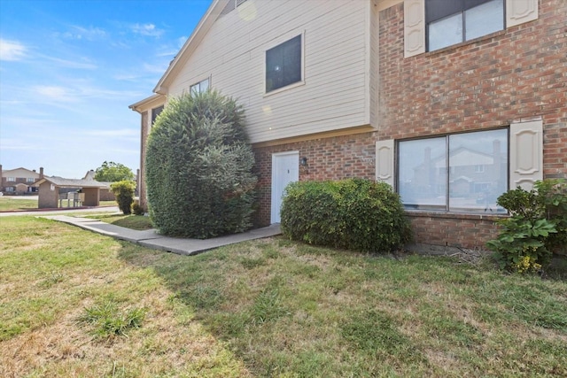 view of home's exterior with a lawn and brick siding