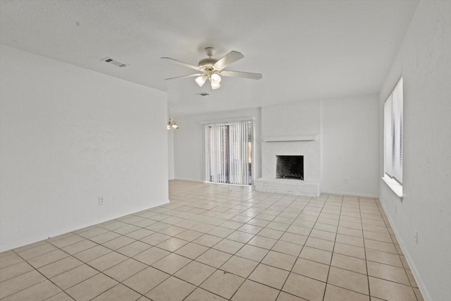unfurnished living room with a fireplace, visible vents, a ceiling fan, and light tile patterned floors