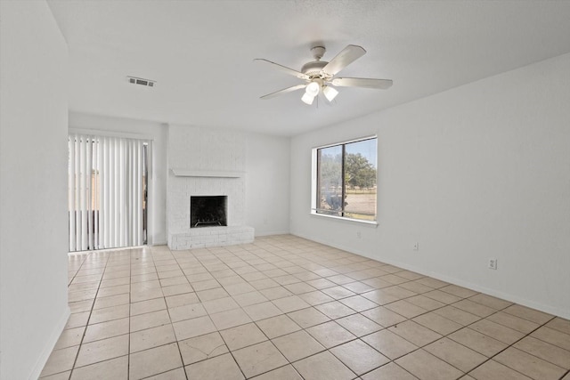 unfurnished living room with a ceiling fan, light tile patterned floors, baseboards, a brick fireplace, and visible vents
