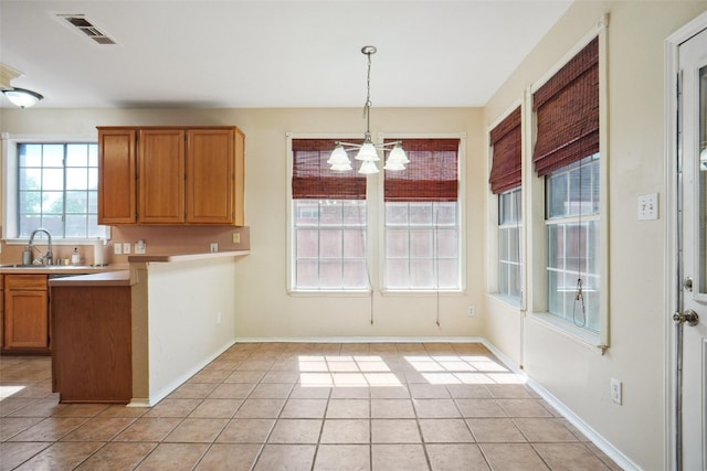 kitchen with light countertops, visible vents, light tile patterned floors, a chandelier, and hanging light fixtures