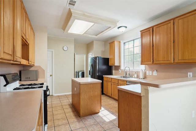 kitchen with a sink, gas range, light countertops, visible vents, and a kitchen island