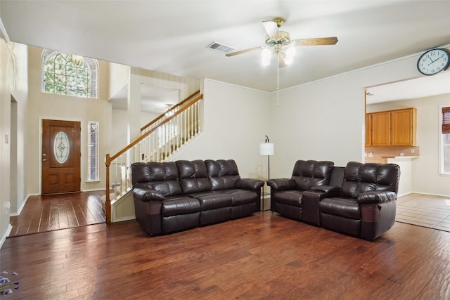 living area with visible vents, baseboards, hardwood / wood-style flooring, stairs, and ceiling fan