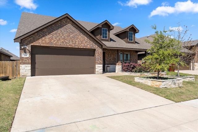 view of front of property featuring stone siding, an attached garage, fence, brick siding, and roof with shingles