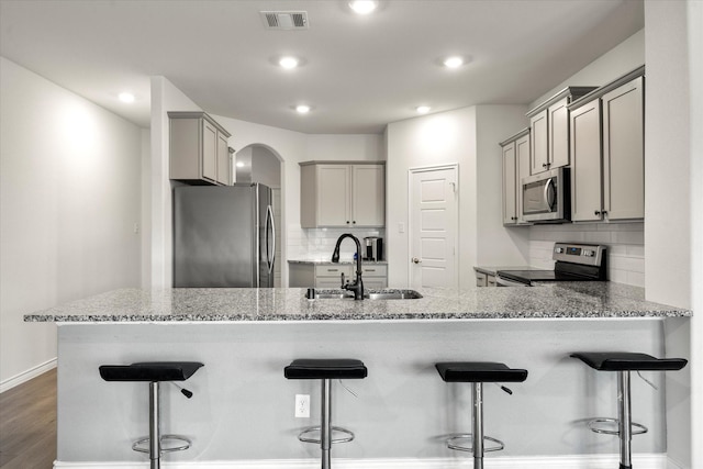 kitchen with stainless steel appliances, visible vents, a sink, gray cabinetry, and a peninsula