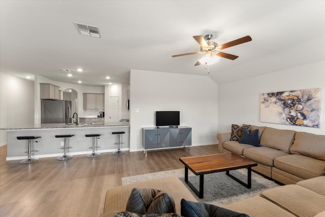 living room with arched walkways, baseboards, visible vents, wood finished floors, and ceiling fan