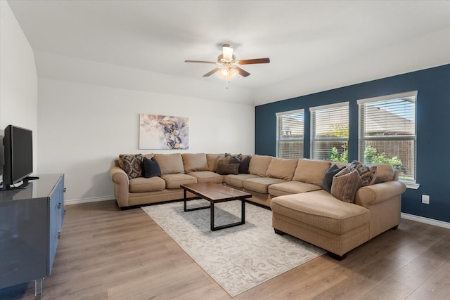 living area featuring ceiling fan, baseboards, and light wood-style floors