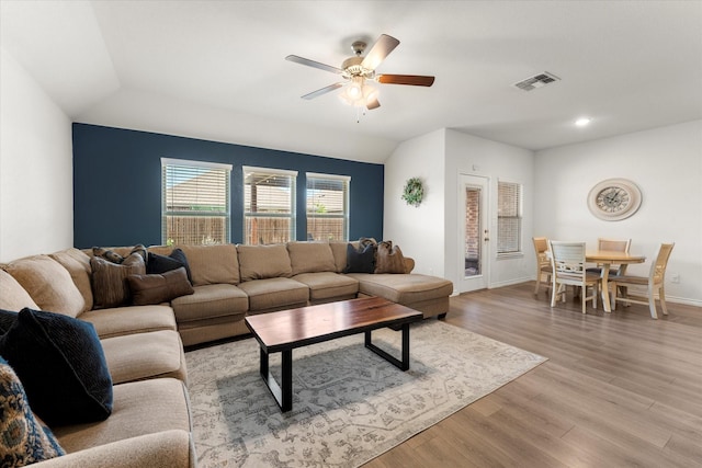 living area featuring light wood-style flooring, ceiling fan, baseboards, lofted ceiling, and visible vents