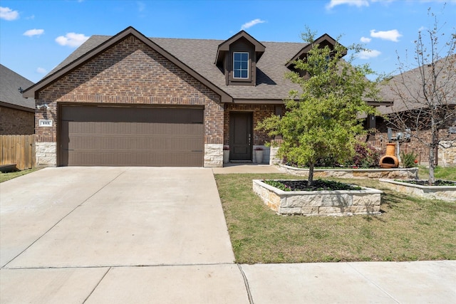 view of front of home with driveway, brick siding, stone siding, roof with shingles, and a garage