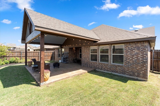rear view of house featuring a fenced backyard, brick siding, a yard, and a patio