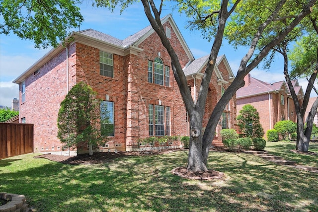 view of side of property featuring fence, brick siding, and a yard