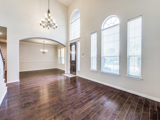 foyer entrance with wood finished floors, arched walkways, an inviting chandelier, baseboards, and a high ceiling