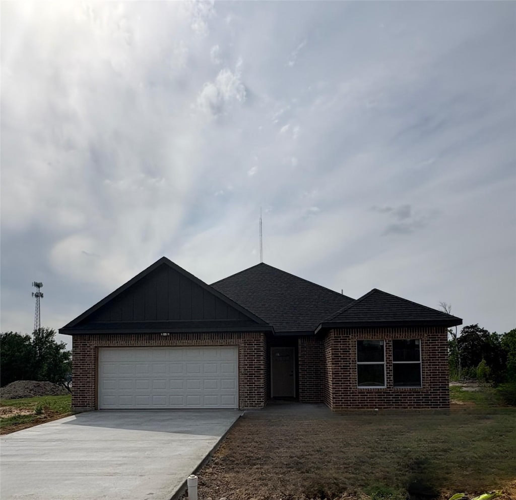 single story home with driveway, an attached garage, brick siding, and roof with shingles