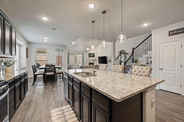 kitchen with dishwasher, visible vents, a sink, light wood-style flooring, and open floor plan