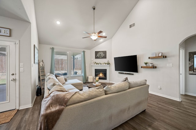 living room featuring dark wood finished floors, a glass covered fireplace, visible vents, and baseboards