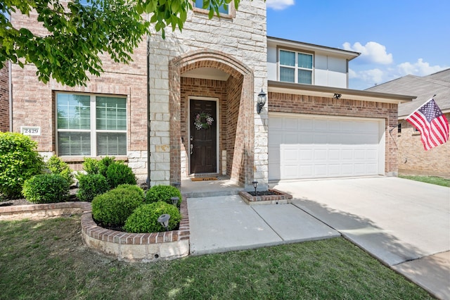 doorway to property with brick siding, driveway, stone siding, and a garage