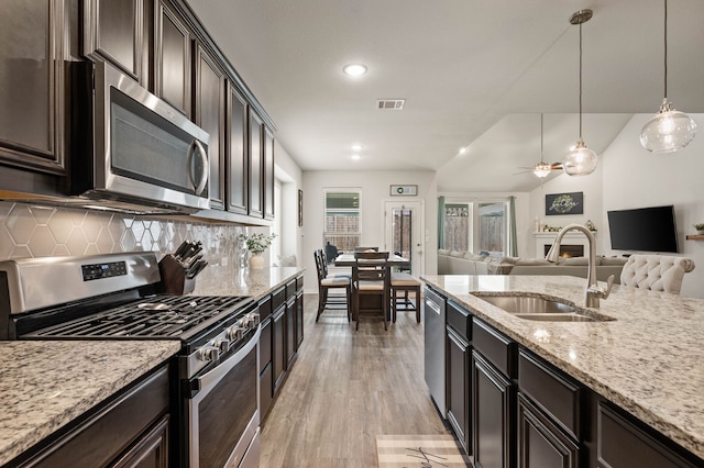 kitchen featuring a sink, light wood-type flooring, visible vents, backsplash, and appliances with stainless steel finishes