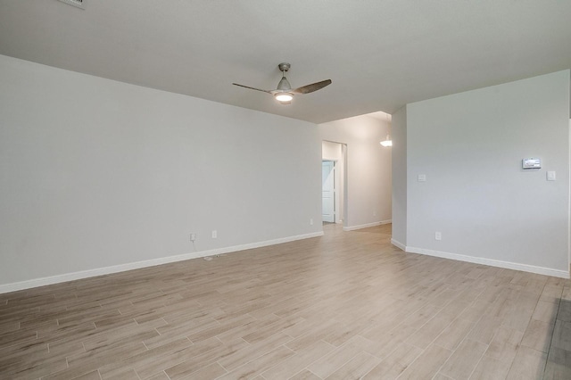 spare room with baseboards, a ceiling fan, and light wood-style flooring
