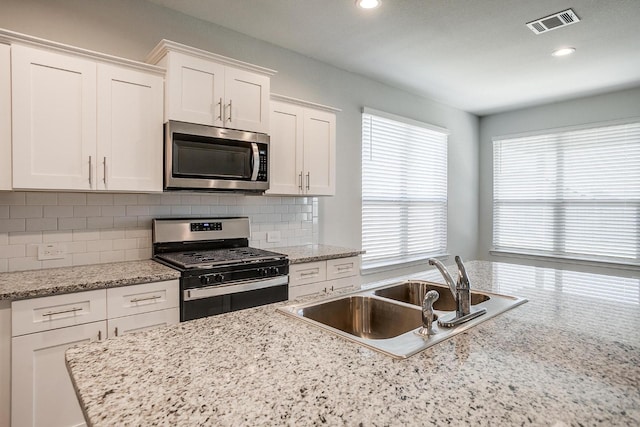 kitchen featuring a sink, white cabinets, stainless steel appliances, and a healthy amount of sunlight