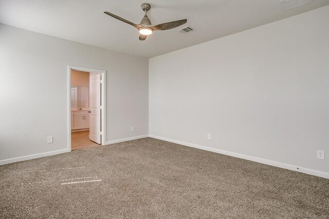 empty room with baseboards, ceiling fan, light colored carpet, and visible vents