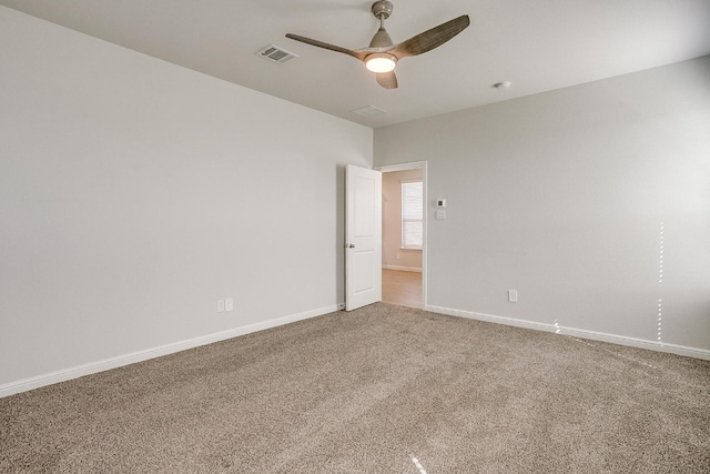 unfurnished room with visible vents, a ceiling fan, baseboards, and carpet floors