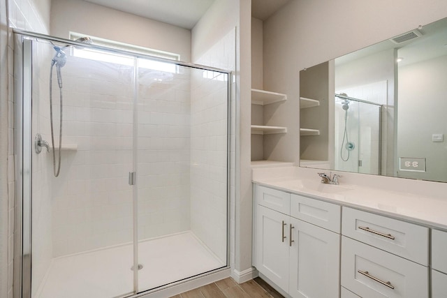 full bath featuring vanity, visible vents, wood finished floors, and a stall shower