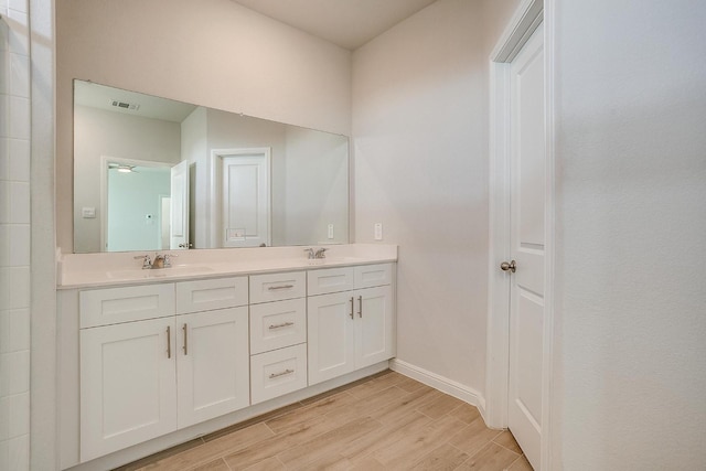 bathroom with visible vents, a sink, wood finished floors, and double vanity