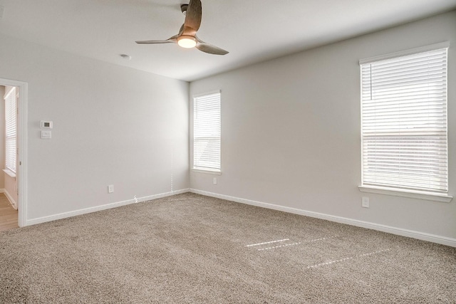 carpeted empty room with ceiling fan and baseboards