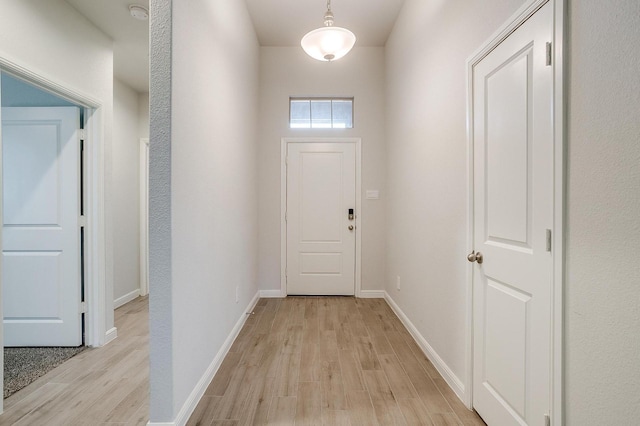 doorway to outside with baseboards and light wood-type flooring