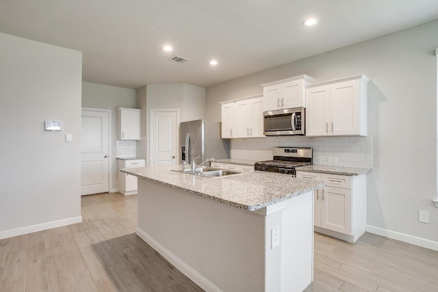 kitchen featuring visible vents, light wood-type flooring, tasteful backsplash, a sink, and appliances with stainless steel finishes