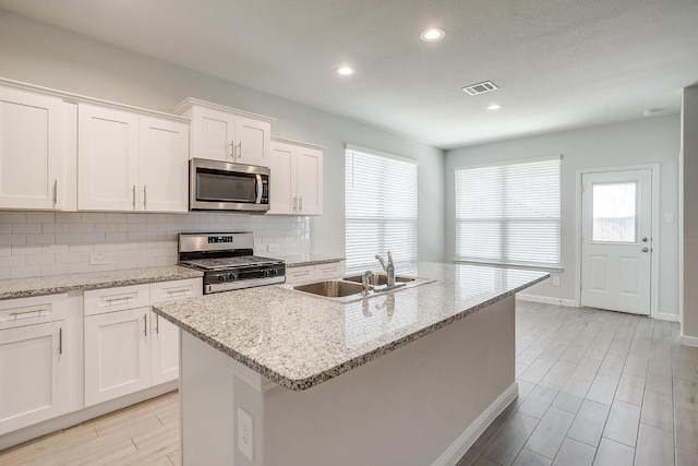 kitchen featuring visible vents, appliances with stainless steel finishes, tasteful backsplash, wood finish floors, and a sink