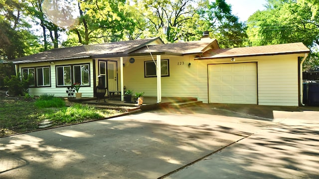 ranch-style home featuring a garage, a shingled roof, a chimney, and concrete driveway