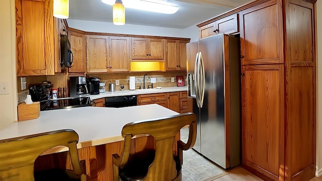kitchen featuring black appliances, a peninsula, a sink, and light countertops