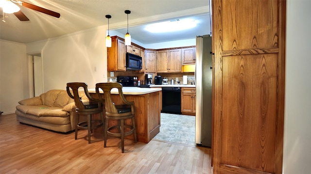 kitchen with light wood-style floors, black appliances, a peninsula, a kitchen bar, and ceiling fan