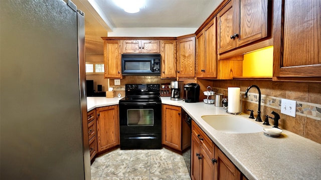 kitchen featuring brown cabinetry, a sink, black appliances, and tasteful backsplash