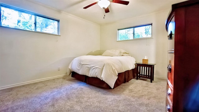 carpeted bedroom with crown molding, baseboards, and ceiling fan